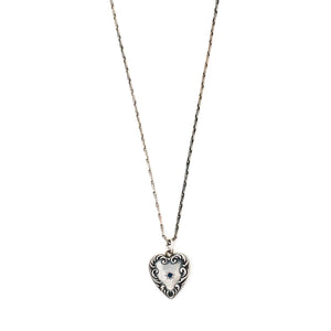 This heart charm is made of sterling silver and features a single blue cabochon stone inlaid in a star setting, and surrounded by a raised and textured border. The initials "AK" are finely etched on the back. Paired with one of our antique silver chains, this heart pendant can be worn both as a pendant or in a cluster of charms. Front charm view, shown on chain