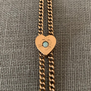 This 12K gold fill antique curb watch chain measures 25" in length doubled.  It features a gold fill heart shaped slide adornment with an etched flower with  an opal at its center. Doubled up, this chain is striking with a gold locket or on its own. Close up of opal heart slide