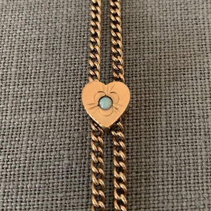 This 12K gold fill antique curb watch chain measures 25" in length doubled. It features a gold fill heart shaped slide adornment with an etched flower with an opal at its center. Doubled up, this chain is striking with a gold locket or on its own. Close up of opal heart slide