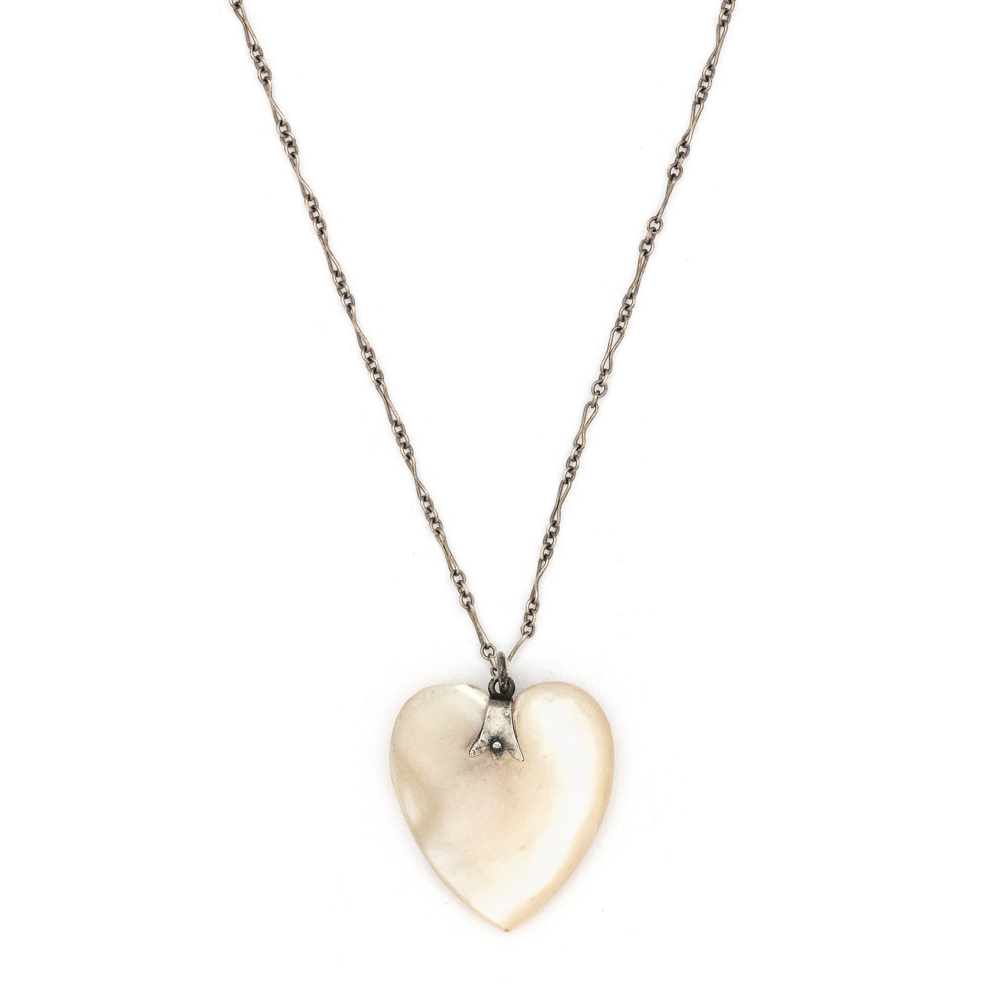 This sweet heart shaped Victorian mother of pearl pendant is beautifully iridescent and features a sterling silver bail. Paired with one of our antique silver chains, this charm can be worn both as a pendant or in a cluster of charms.  Front charm view