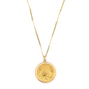 This incredibly detailed round locket features a raised relief rose and branches with three white paste stones throughout the design. The letters JMR are inscribed on the back. It opens to hold two photos, includes one original frame and pairs perfectly with one of our antique gold fill chains. Front Locket View, shown on chain