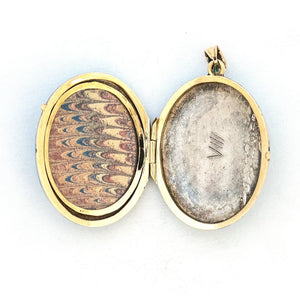 This 14K gold oval locket features pearls at the center of an intricate forget-me-not flower with a rich robin egg blue enamel background. It opens to hold two photos, includes one original frame and pairs perfectly with one of our antique 14K gold chains. Open locket view