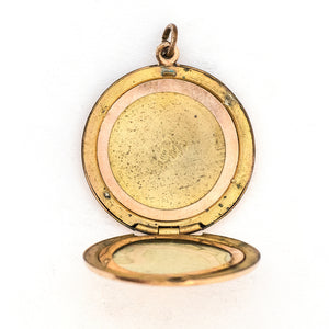 This round locket features a delicately etched wreath of forget-me-not flowers with purple paste stones throughout the design as the flower centers. The initials EM are inscribed on the back. It opens to hold two photos, includes both original frames and pairs perfectly with one of our antique gold fill chains. Open locket view