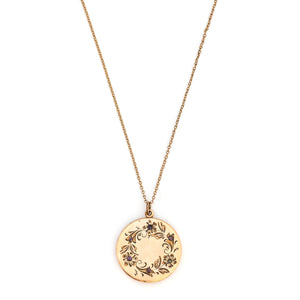 This round locket features a delicately etched wreath of forget-me-not flowers with purple paste stones throughout the design as the flower centers. The initials EM are inscribed on the back. It opens to hold two photos, includes both original frames and pairs perfectly with one of our antique gold fill chains. Front Locket View shown on chain