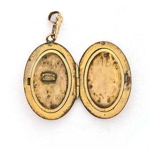 This oval locket features a genuine diamond atop a delicately etched forget-me-not flower with vines draped around it. It opens to hold two photos, includes both original frames and pairs perfectly with one of our antique gold fill chains. Open locket view