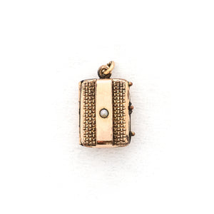 This petite rectangular locket features a basket weave pattern with a seed pearl on one side and a strip of black onyx on the other. It opens to hold two photos, includes both original frames and glass and pairs perfectly with one of our antique gold fill chains. Front Locket view