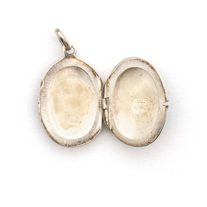 This oval sterling silver vintage locket features banded dark green malachite at its center with a beautifully etched leafed design on the back . It opens to hold two photos and pairs perfectly with one of our antique sterling silver chains. Open locket view