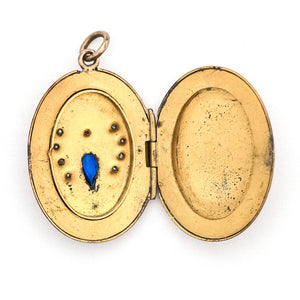 This unique oval Victorian locket features blue and red stones and seed pearls set within a finely etched bug design. It opens to hold one photo, and pairs perfectly with one of our antique gold fill chains. Open locket view