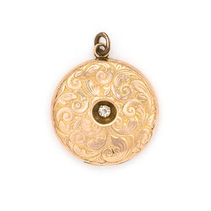 This romantic round Edwardian locket features a playful swirling pattern framing a sizable white paste stone at its center, and a polished verso. It opens to hold two photos, includes both original frames and pairs perfectly with one of our antique gold fill chains. Front locket view
