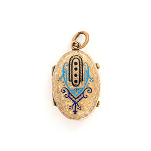 This unique oval locket features a delicate design with sky, navy blue and black enamel set on a finely textured background. The background features floral accents and a cross bar in the same instricate style. It opens to hold two photos, includes both original frames and glass and pairs perfectly with one of our antique gold fill chains. Front locket view
