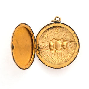 This detailed round locket features an intricate pattern reminiscent of rolling waves with two blue and one multicolored glass stones at it's center. It opens to hold two photos and pairs perfectly with one of our antique gold fill chains. Open locket view