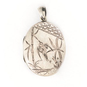 This large oval sterling silver locket features a finely etched swallow and bamboo scene, complete with rolling hills in the back drop. It opens to hold two photos and pairs perfectly with one of our antique sterling silver chains. Front locket view