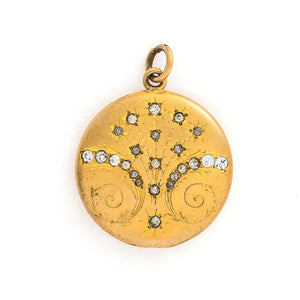 This matte round locket features 23 white glass stones scattered throughout a whimsical pattern of starbursts and ornamental swirls. It opens to hold one photo, includes the original frame and pairs perfectly with one of our antique gold fill chains. Front locket view