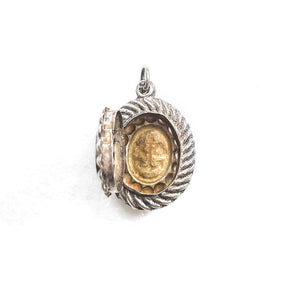 This oval sterling silver locket features an anchor, heart and cross at its center with surrounding filigree and rope patterns. The back of the locket is the same as the front. It opens to hold one photo and pairs perfectly with one of our antique sterling silver chains. Open locket view