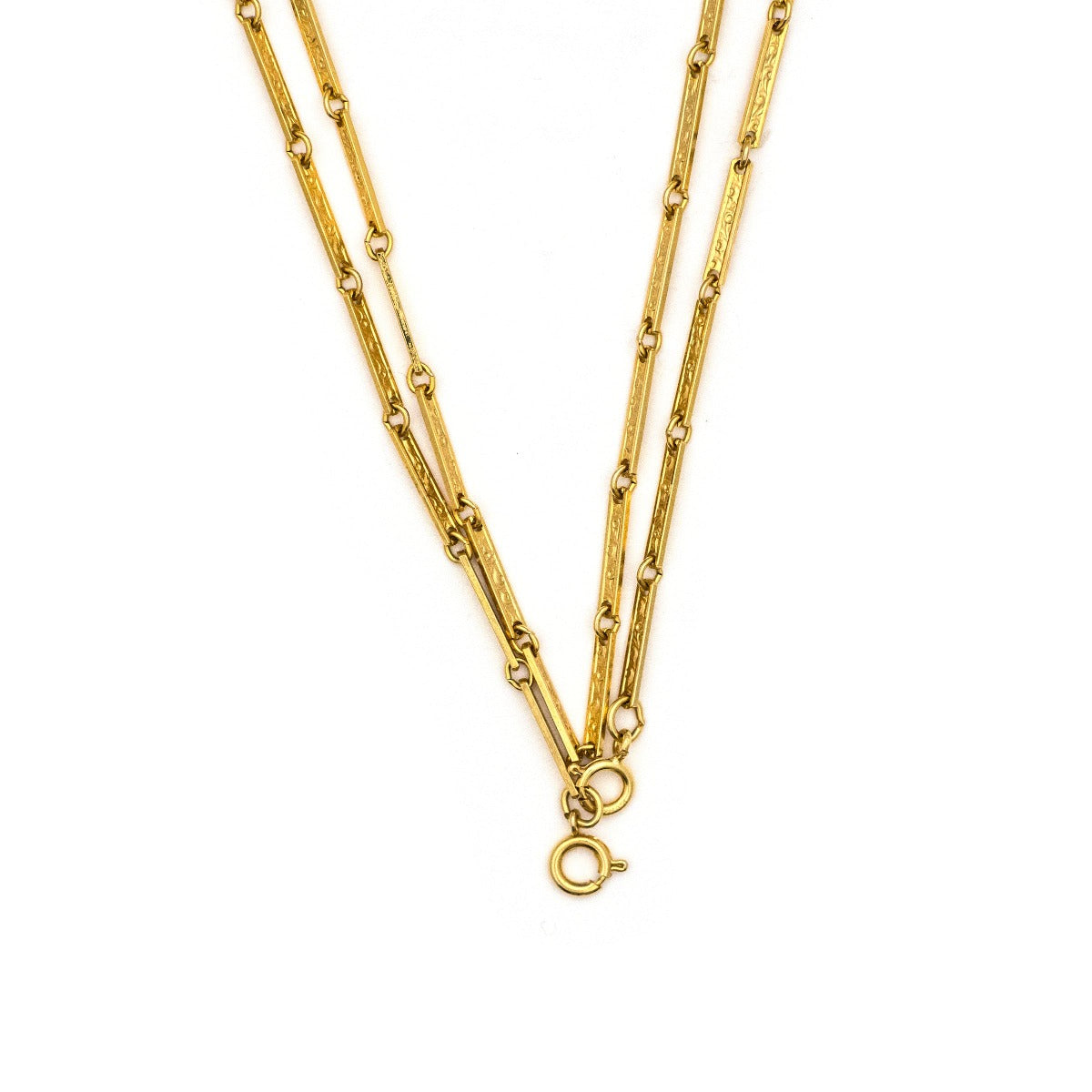 This 50" gold fill bar link chain is made up of delicate bar links, each intricately etched with an ornate, swirling design. Paired with one of our antique gold lockets or on its own, this chain makes for a delicate yet strong statement necklace. Close up view of clasp