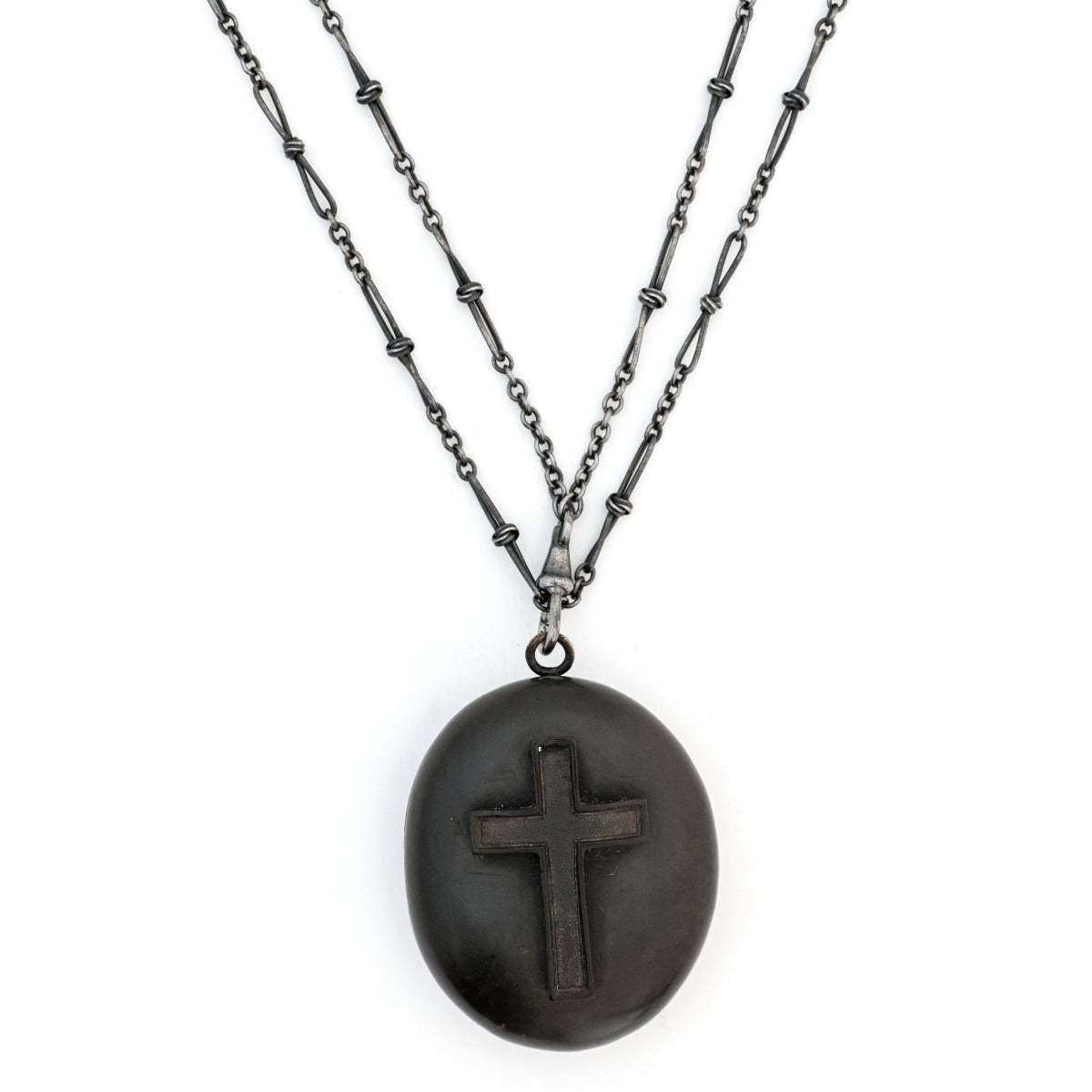 Gutta percha cross antique locket, front view, raised cross, black antique locket