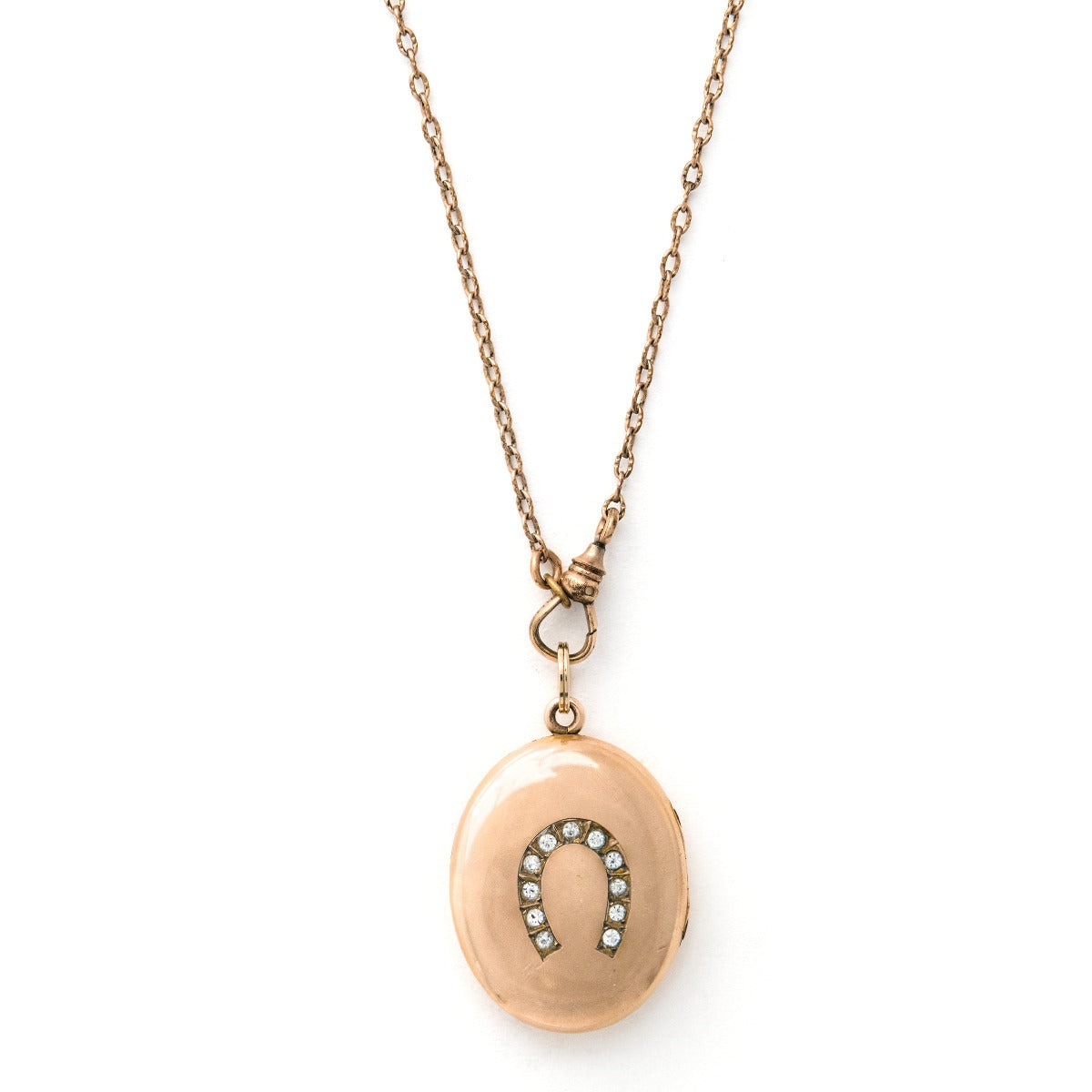 Oval horseshoe antique locket on antique gold fill watch chain, front view. Gold fill locket and chain with white paste stones