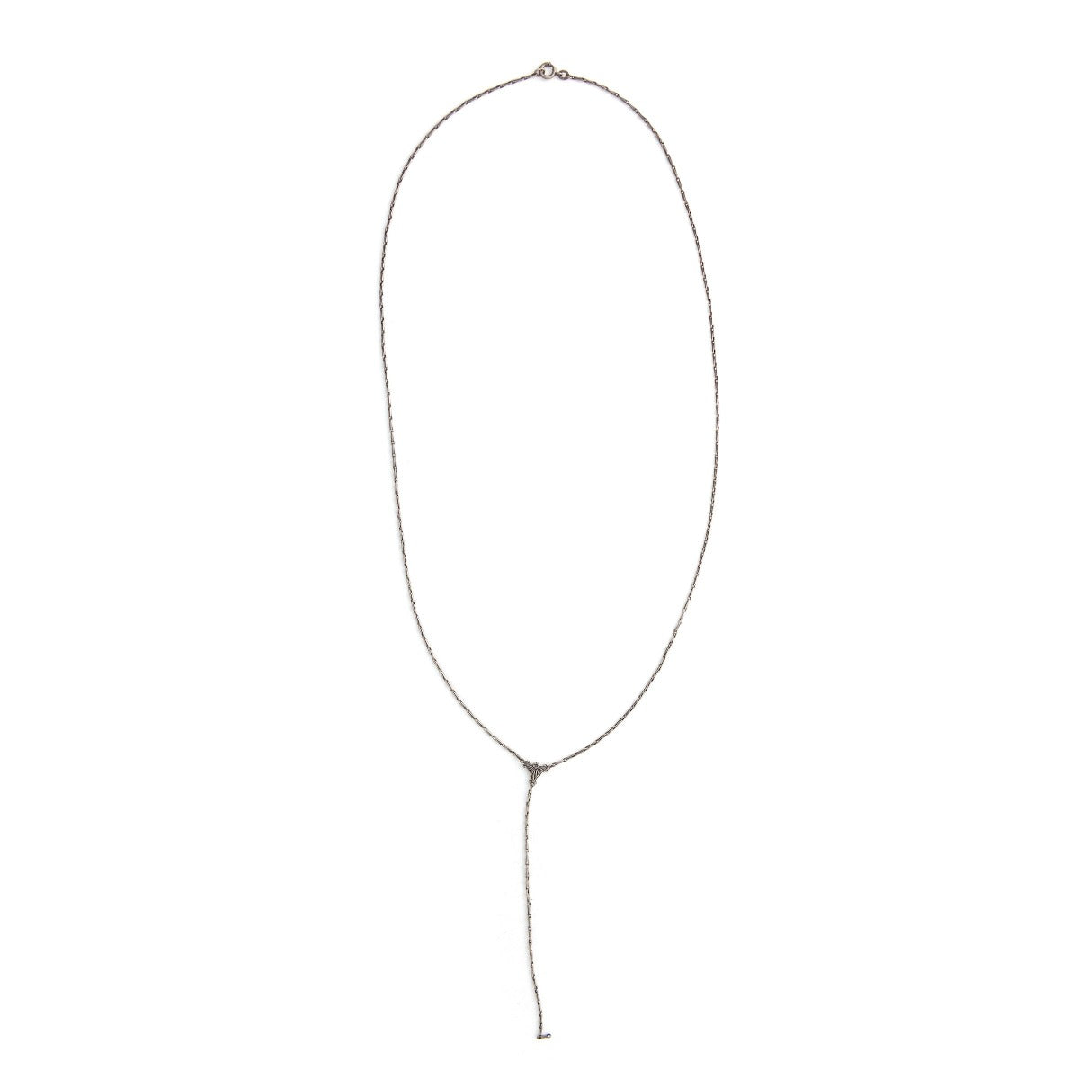 This Victorian era silver lariat chain measures 26" in length with a 4.5" extension. It features a delicate fancy bar link style and an ornamental triangle at the base of the extension. This classic Victorian style chain pairs beautifully with one of our vintage lockets or charms. Full chain view