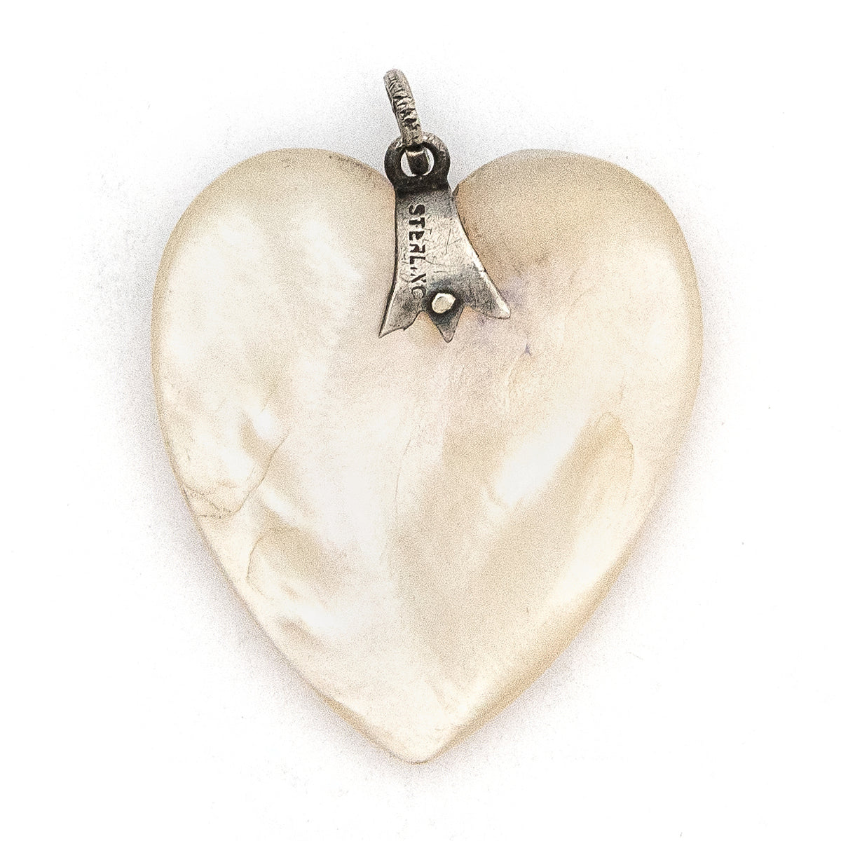 This sweet heart shaped Victorian mother of pearl pendant is beautifully iridescent and features a sterling silver bail. Paired with one of our antique silver chains, this charm can be worn both as a pendant or in a cluster of charms.  Back of charm view