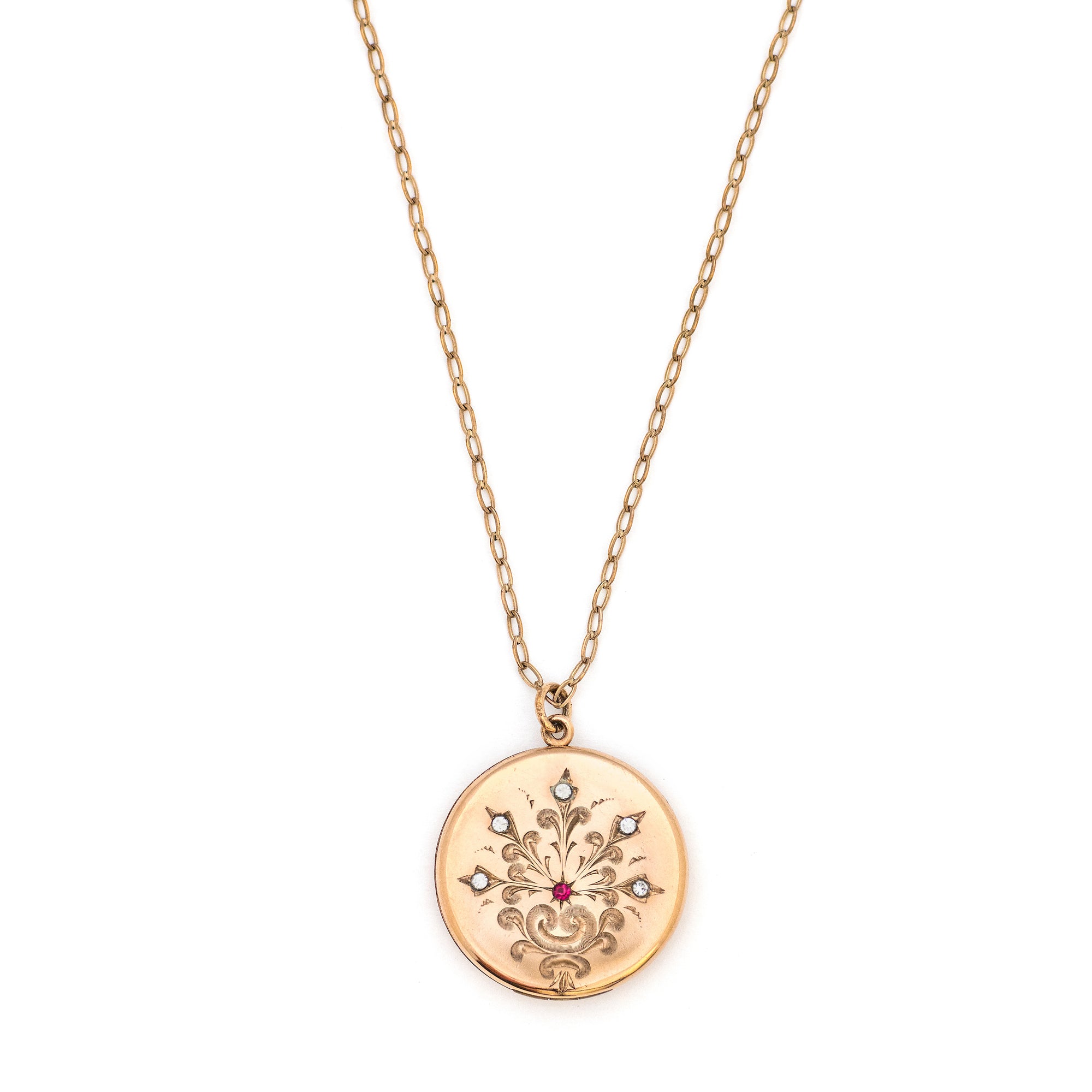 This round Victorian locket features a playful design which uses curlicues and flourishes to enhance the white and red paste stones. It opens to hold two photos, includes both original frames and pairs perfectly with one of our antique gold fill chains.  Front Locket view