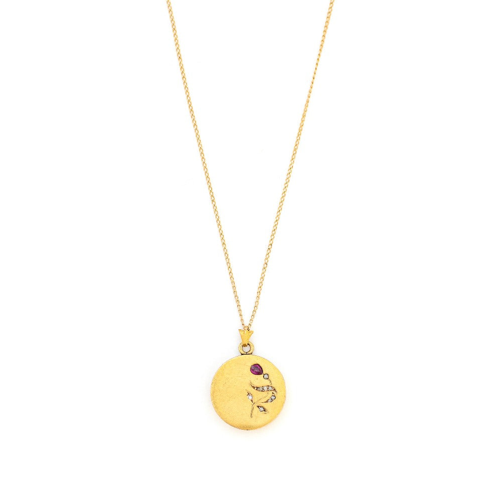 This petite 14K gold round locket features a whimsical floral design encrusted with 8 diamonds and a pear shaped ruby. It opens to hold two photos, includes one original frame and pairs perfectly with one of our antique 14K gold chains.  Front Locket View, shown on chain