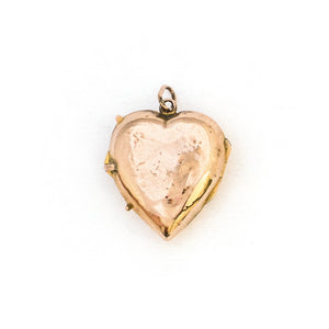This puffed three dimensional 10K gold heart locket features a swirling raised relief curlicue pattern with a pearl, ruby and sapphire accent. It opens to hold two photos, includes both original frames and pairs perfectly with one of our antique 14K gold chains.  Back Locket view