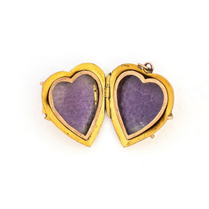 This puffed three dimensional 10K gold heart locket features a swirling raised relief curlicue pattern with a pearl, ruby and sapphire accent. It opens to hold two photos, includes both original frames and pairs perfectly with one of our antique 14K gold chains.  Open Locket View