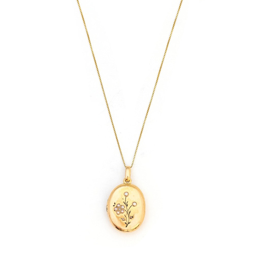This 18K gold oval locket features 10 pearls scatters throughout a delicate floral design complete with black enamel details. It opens to hold two photos pairs perfectly with one of our antique 14K gold chains. Front Locket View, shown on chain