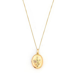 This 18K gold oval locket features 10 pearls scatters throughout a delicate floral design complete with black enamel details. It opens to hold two photos pairs perfectly with one of our antique 14K gold chains. Front Locket View, shown on chain