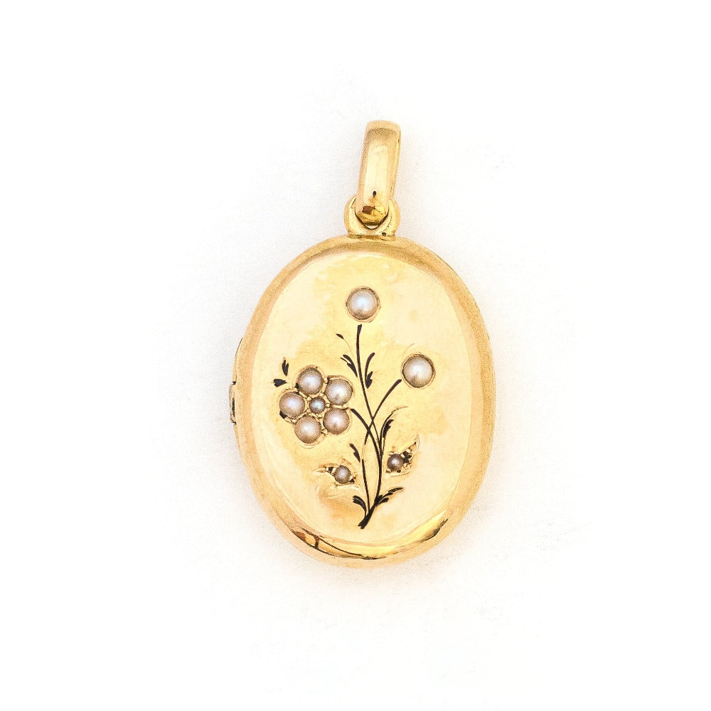 This 18K gold oval locket features 10 pearls scatters throughout a delicate floral design complete with black enamel details. It opens to hold two photos pairs perfectly with one of our antique 14K gold chains. Front Locket View