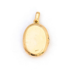 This 18K gold oval locket features 10 pearls scatters throughout a delicate floral design complete with black enamel details. It opens to hold two photos pairs perfectly with one of our antique 14K gold chains. Back locket view