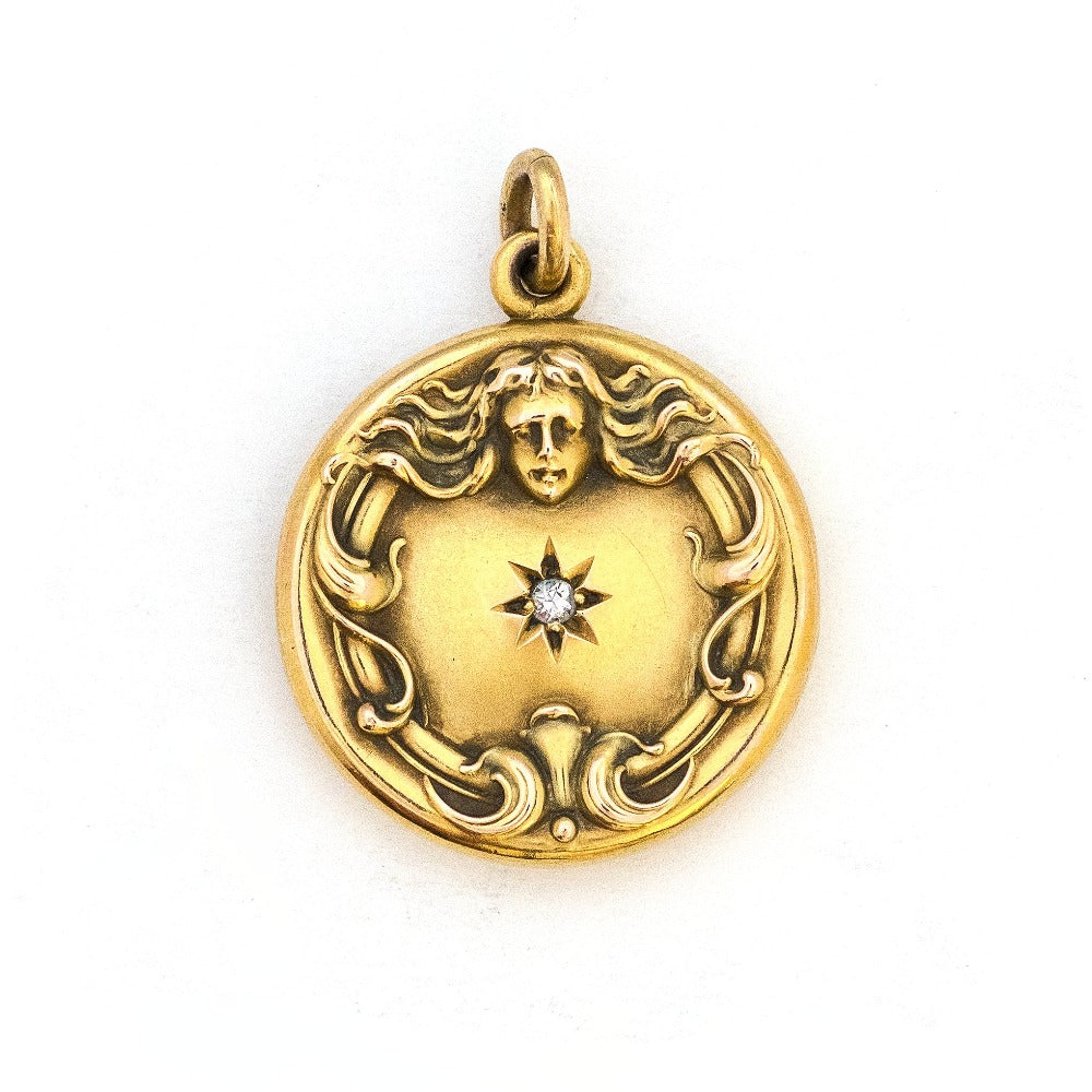 This breathtaking 14K gold locket features a woman in raised relief with her hair swirling around the lockets perimeter and a Victorian starburst with a 3 point diamond at its center. The initials MN are elegantly inscribed on the back. It opens to hold two photos, includes both original frames and pairs perfectly with one of our antique 14K gold chains. Front Locket view