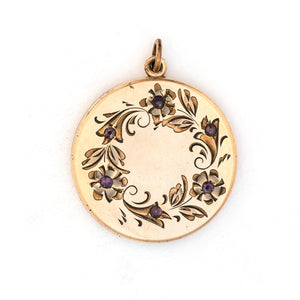 This round locket features a delicately etched wreath of forget-me-not flowers with purple paste stones throughout the design as the flower centers. The initials EM are inscribed on the back. It opens to hold two photos, includes both original frames and pairs perfectly with one of our antique gold fill chains.  Front Locket View