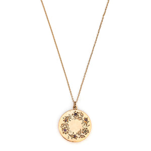 This round locket features a delicately etched wreath of forget-me-not flowers with purple paste stones throughout the design as the flower centers. The initials EM are inscribed on the back. It opens to hold two photos, includes both original frames and pairs perfectly with one of our antique gold fill chains.  Front Locket View shown on chain