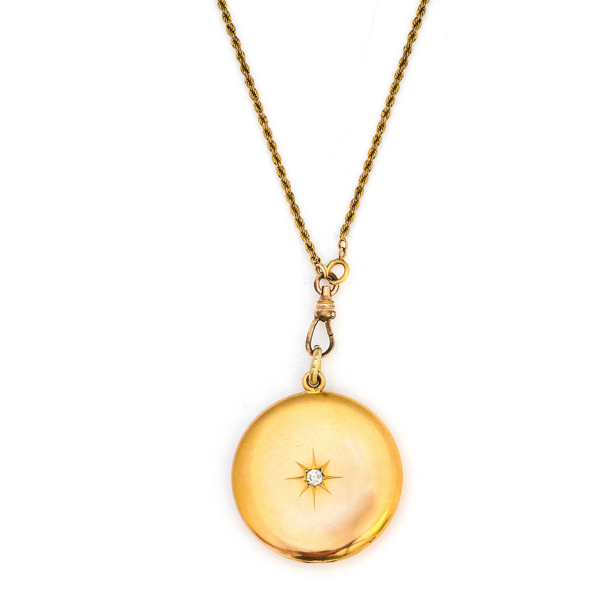 This large round locket features a classic Victorian starburst with a 3.5 mm white paste stone at the center. It opens to hold two photos, includes both original frames and pairs perfectly with one of our antique gold fill chains. Front Locket view, shown on chain