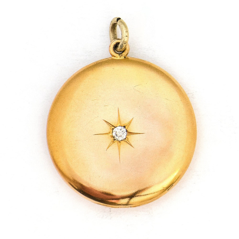 This large round locket features a classic Victorian starburst with a 3.5 mm white paste stone at the center. It opens to hold two photos, includes both original frames and pairs perfectly with one of our antique gold fill chains. Front Locket view