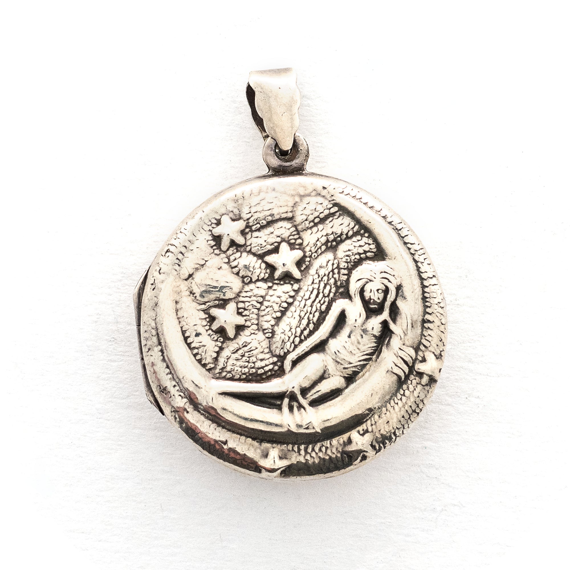 This round sterling silver Victorian locket features a woman lying in a crescent moon surrounded by stars. It opens to hold two photos and pairs perfectly with one of our antique sterling silver chains.  Front locket view