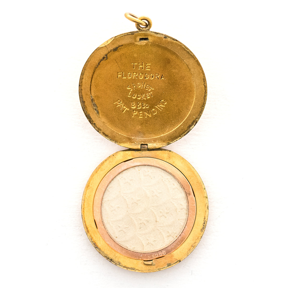 This incredibly unique gold fill locket features red and white paste stones surrounding a central starburst. This locket has two compartments: one that holds a photo, original frame included, and a second secret compartment that holds a tiny sachet. The inscribed text inside the locket tells us this design was patent pending (See photos).  We've never seen anything like it! This gem pairs perfectly with one of our antique gold fill chains.  Open locket, showing picture frame
