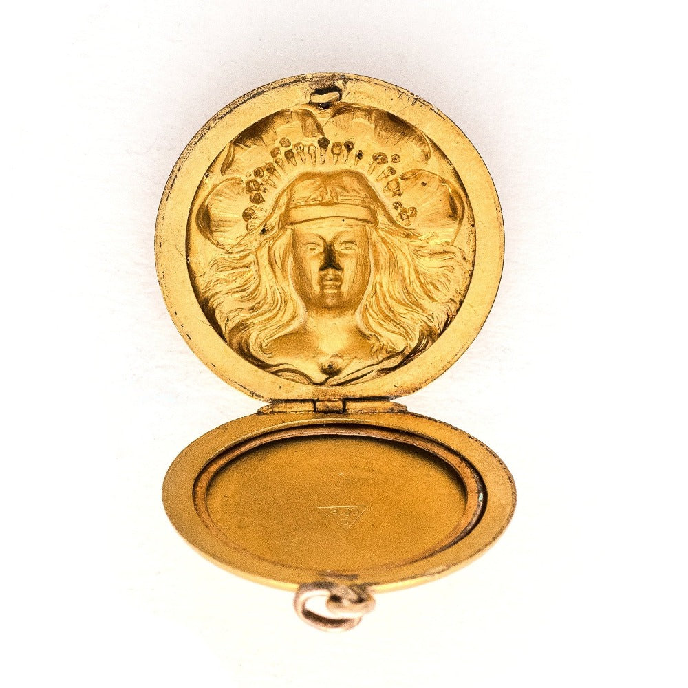 This breathtaking Art Nouveau locket features a woman with flowing hair set in front of a pansy. There are white paste stones scattered throughout the beautiful design. It opens to hold two photos and pairs perfectly with one of our antique gold fill watch chains.  Open Locket view