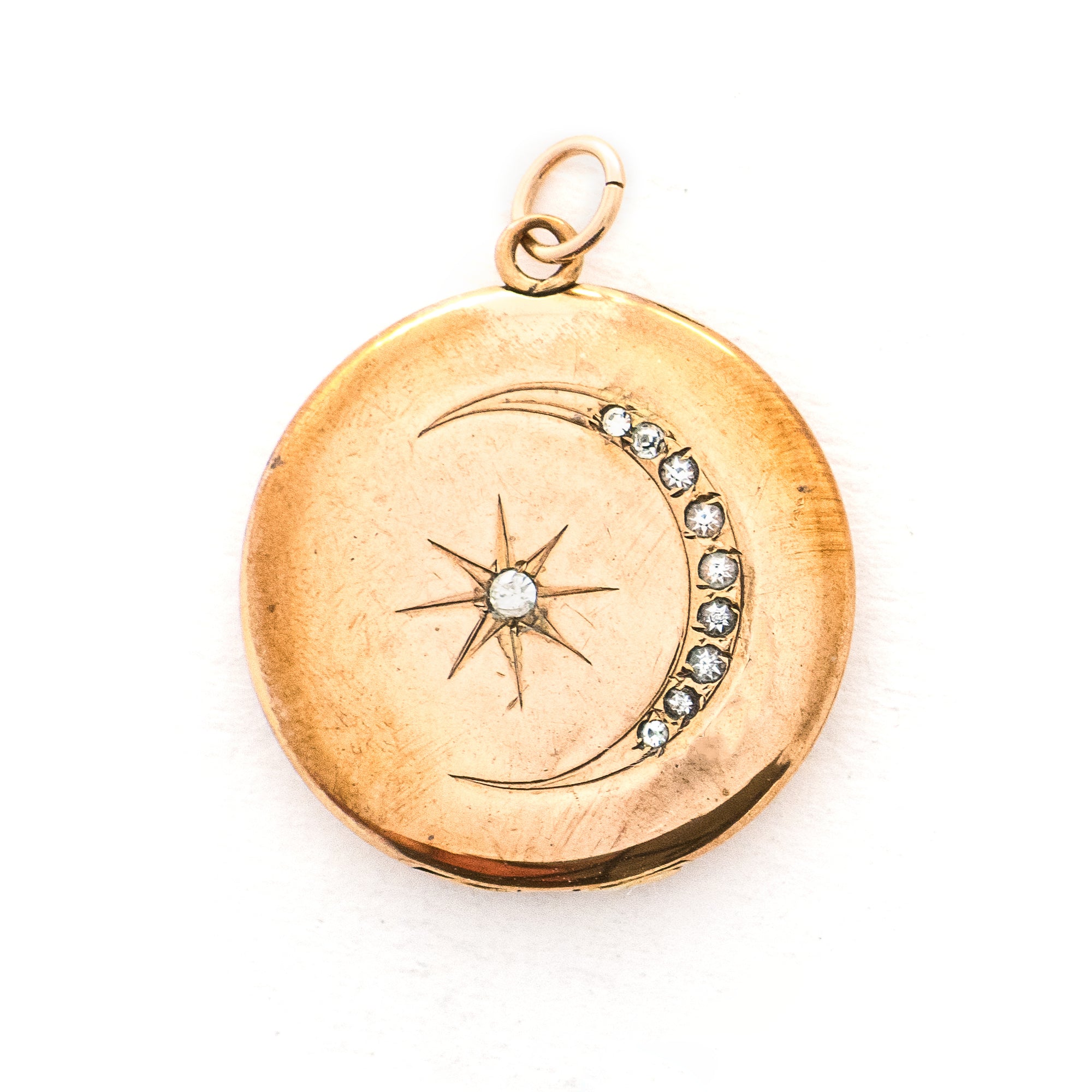 This classic Victorian locket features a large crescent moon surrounding a bright starburst with 10 white Victorian paste stones throughout the design. It opens to hold two photos, includes one original frame and pairs perfectly with one of our antique gold fill chains.  Front locket view