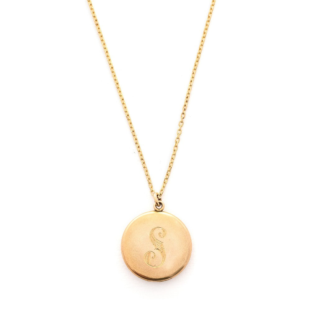 This round, matte locket features an ornate "S" in Victorian era script on the front and the initials MLC on the back. It opens to hold two photos, includes both original frames and pairs perfectly with one of our antique gold fill chains. Front locket view, shown on chain