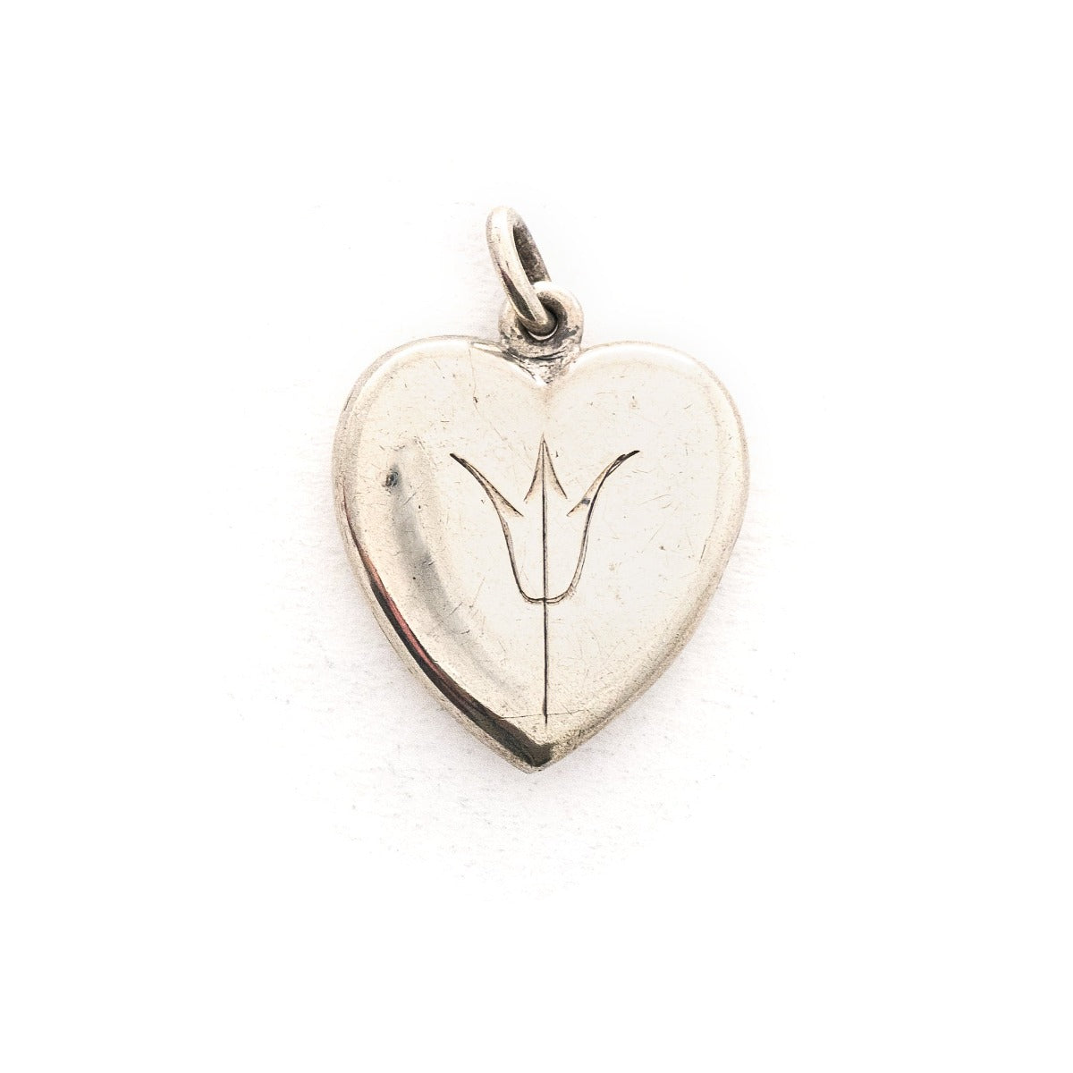 This heart shaped sterling silver locket features a simple and delicately etched tulip. The initials GFD  are inscribed on the back. It opens to hold two photos, includes both original frames and pairs perfectly with one of our vintage sterling silver chains. Front locket view