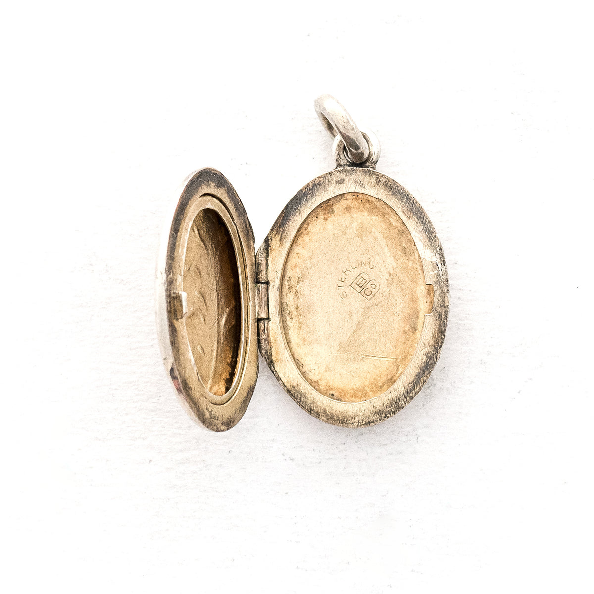 This oval sterling silver locket features two beautiful plumes with tiny flowers at it's base. It opens to hold two photos and pairs perfectly with one of our vintage sterling silver chains. Open locket view