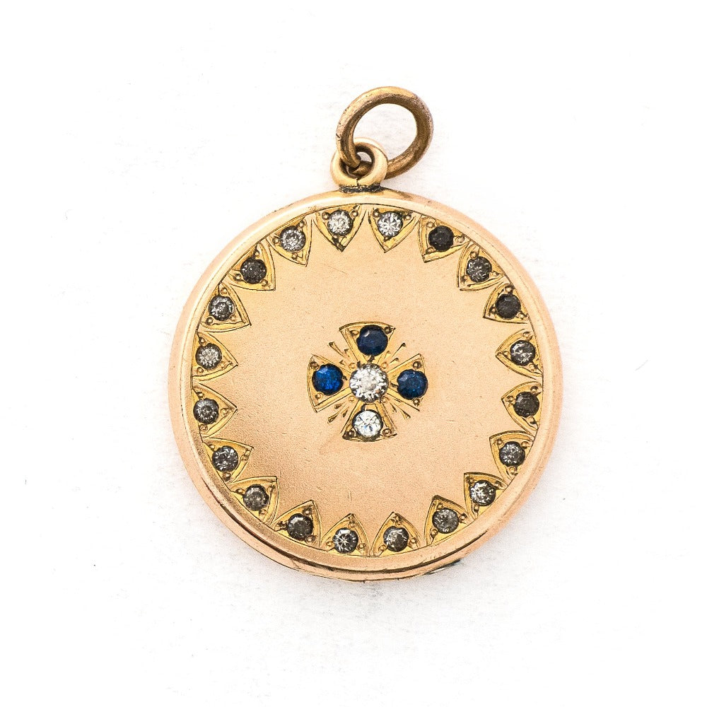 This round locket features a Maltese Cross, a symbol of protection, made up of blue, white and grey paste stones surrounded by a paste stone border. It opens to hold one photo and pairs perfectly with one of our antique gold fill chains.  Front locket view
