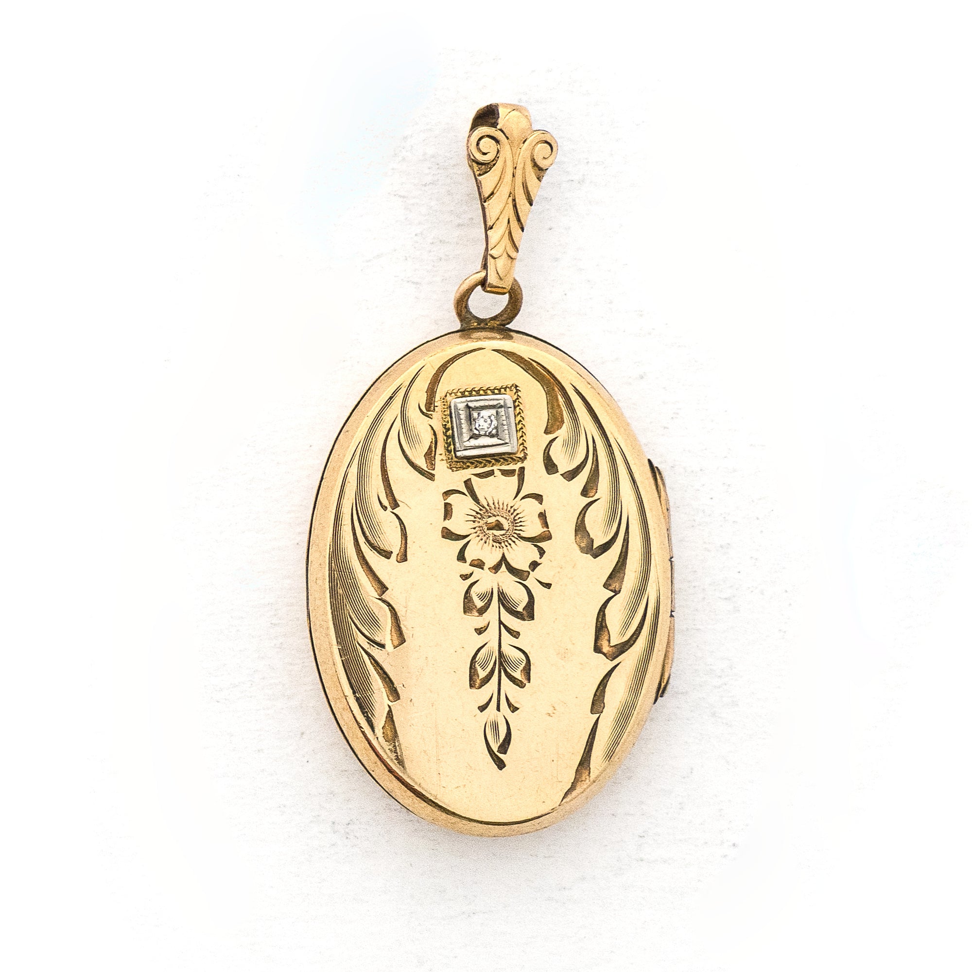 This oval locket features a genuine diamond atop a delicately etched forget-me-not flower with vines draped around it. It opens to hold two photos, includes both original frames and pairs perfectly with one of our antique gold fill chains. Front Locket View