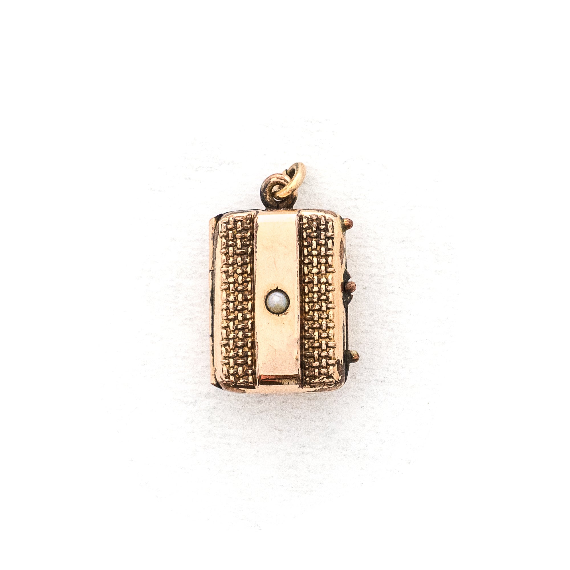 This petite rectangular locket features a basket weave pattern with a seed pearl on one side and a strip of black onyx on the other. It opens to hold two photos, includes both original frames and glass and pairs perfectly with one of our antique gold fill chains.  Front Locket view
