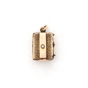 This petite rectangular locket features a basket weave pattern with a seed pearl on one side and a strip of black onyx on the other. It opens to hold two photos, includes both original frames and glass and pairs perfectly with one of our antique gold fill chains.  Front Locket view