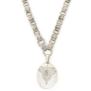 This large sterling silver oval locket features the classic Victorian symbol, a forget-me-not flower surrounded by greenery in a dramatic deep V shape and opens to hold two photos. We have paired this locket with an exquisite engraved Victorian sterling silver book chain from the same era. Front locket view on chain
