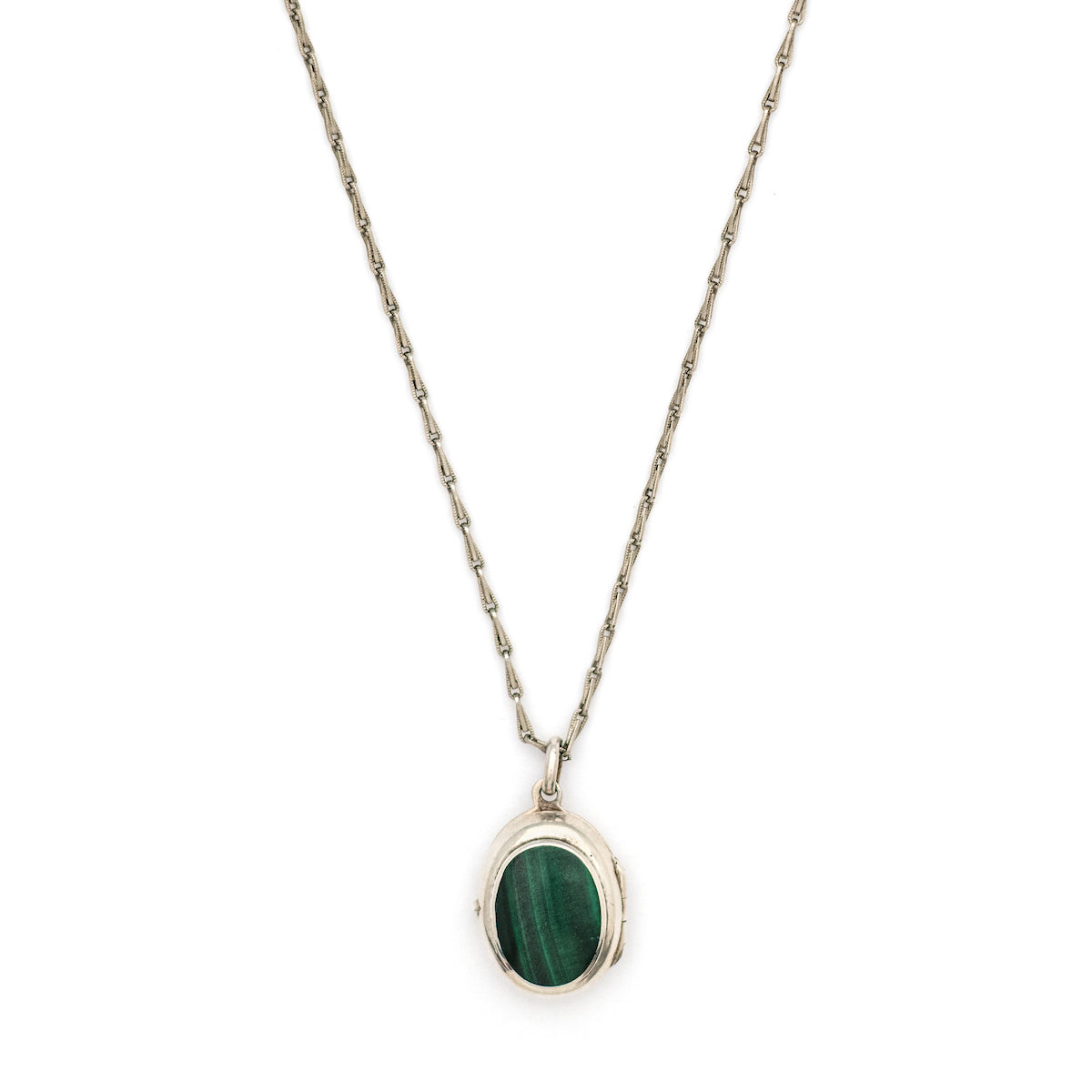 This oval sterling silver vintage locket features banded dark green malachite at its center with a beautifully etched leafed design on the back . It opens to hold two photos and pairs perfectly with one of our antique sterling silver chains. Front locket view
