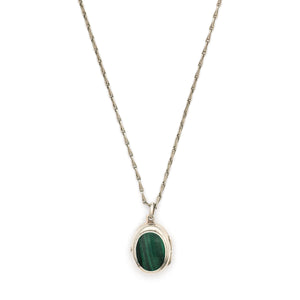 This oval sterling silver vintage locket features banded dark green malachite at its center with a beautifully etched leafed design on the back . It opens to hold two photos and pairs perfectly with one of our antique sterling silver chains. Front locket view, shown on chain